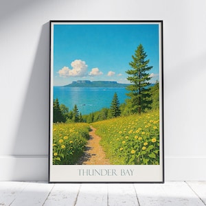 Puede incluir: Impresión artística enmarcada que representa un paisaje de Thunder Bay. Un sendero serpentea a través de un campo de flores amarillas hacia un lago y montañas bajo un cielo azul. El texto "THUNDER BAY" está en la parte inferior, en un marco rectangular.