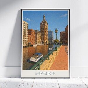 Könnte beinhalten: Ein gerahmter Druck mit einer malerischen Ansicht von Milwaukee, Wisconsin. Das Kunstwerk zeigt einen Fluss mit Gebäuden, Booten und einem Ziegelweg. Das Bild enthält einen hohen Uhrturm und den Namen der Stadt am unteren Rand.