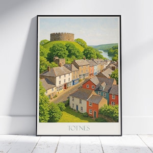 Puede incluir: Un póster enmarcado que muestra una vista panorámica de Totnes, Inglaterra. La obra de arte representa un pueblo histórico con edificios coloridos, una carretera sinuosa y un castillo en una colina. La palabra "TOTNES" está impresa en la parte inferior.