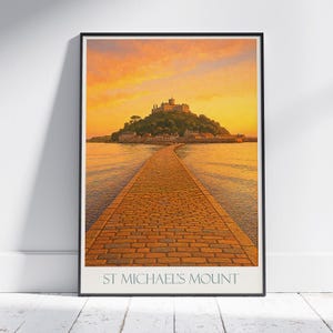 May include: A framed print depicting St Michael's Mount at sunset. A stone causeway leads to the island, topped by a castle. The sky is a blend of orange and yellow, reflected in the water.