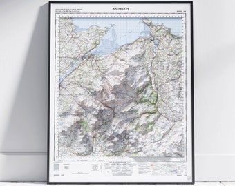 May include: A vintage map of Snowdon, Wales, printed on paper and framed in black. The map shows the surrounding area, including the coastline and mountains. The title "Snowdon" is printed at the top of the map.