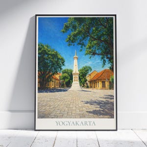 Può includere: Una stampa incorniciata con una vista panoramica di Yogyakarta, Indonesia. L'immagine mostra un alto monumento bianco al centro, circondato da alberi ed edifici con tetti arancioni sotto un cielo blu brillante. La parola "YOGYAKARTA" è stampata in basso.