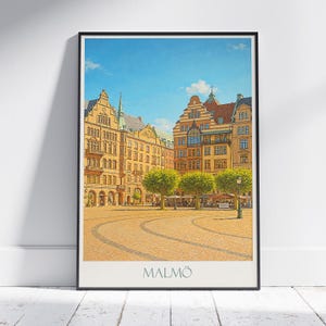 Puede incluir: Una impresión enmarcada que presenta una representación al estilo acuarela de una plaza de ciudad europea. Los edificios son principalmente amarillos y naranjas, con árboles verdes y un cielo azul. La palabra "MALMÖ" está impresa en la parte inferior.