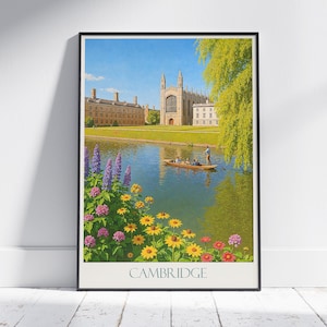 May include: Framed art print featuring a scenic view of Cambridge, England. The image shows a river with a punt carrying passengers, a historic building, and colorful flowers in the foreground. The word "CAMBRIDGE" is printed at the bottom.