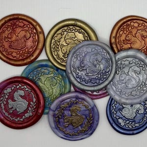 May include: A collection of round wax seals in various colors, including red, gold, blue, and purple. Each seal features a detailed squirrel design within a laurel wreath. The seals are suitable for crafts, scrapbooking, or adding a decorative touch to stationery.