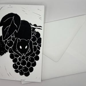 May include: Black and white art print of a rodent eating grapes. The illustration is on a white card with a matching white envelope. The design features a stylized depiction of a mouse or rat amidst a cluster of grapes.