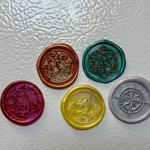 May include: Five colorful wax seals with embossed designs. The seals include a dragon, a ship, a D20 die, a dragon, and a compass rose. The seals are in shades of red, gold, green, yellow, and gray.