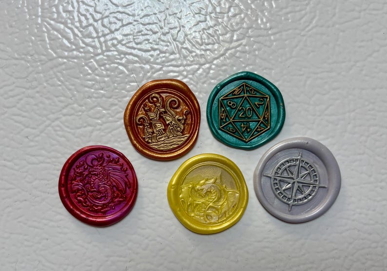 May include: Five colorful wax seals with embossed designs. The seals include a dragon, a ship, a D20 die, a dragon, and a compass rose. The seals are in shades of red, gold, green, yellow, and gray.
