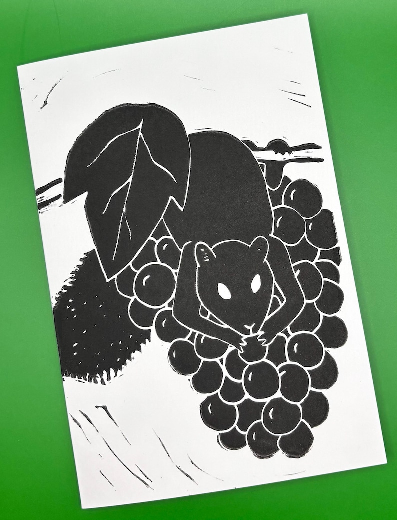 May include: Black and white linocut print of a squirrel eating grapes. The squirrel is in the center, surrounded by a cluster of grapes and a large leaf. The print is on white paper with a green background.