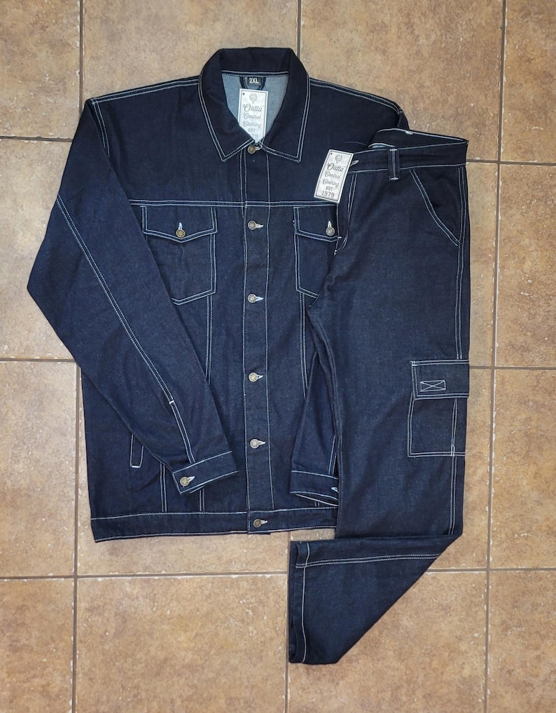 May include: A dark blue denim jacket and matching pants set. The jacket has a button-up front, two chest pockets, and white stitching. The pants have a cargo pocket and white stitching. The set is laid out on a tiled surface.