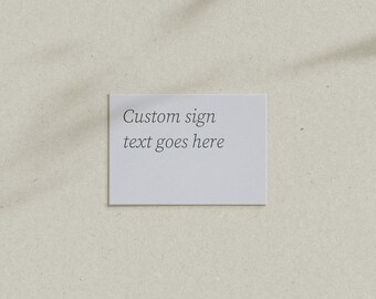 May include: A white card with the text "Custom sign text goes here" on a light beige background.