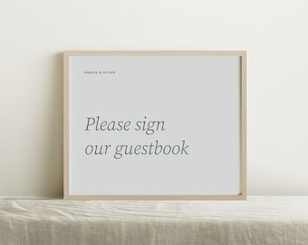 May include: A framed sign with a light wood frame and a white background. The sign says "Please sign our guestbook" and "Harper & Oliver" in a simple black font.