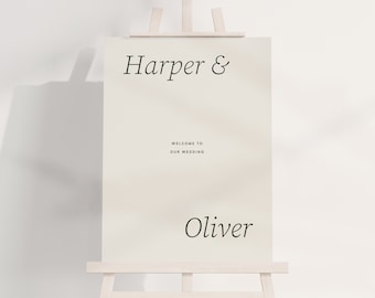 May include: A white welcome sign with black text that reads "Harper & Oliver" and "Welcome to our wedding". The sign is on an easel.