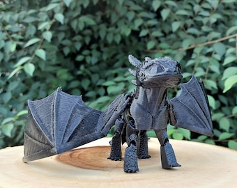 May include: A black articulated dragon figurine with wings outstretched. The dragon has a detailed face and is posed in a standing position.