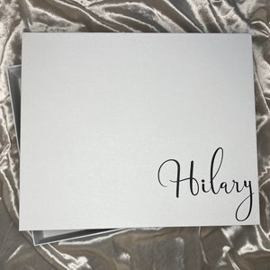 May include: White gift box with a black cursive inscription that reads "Hilary".