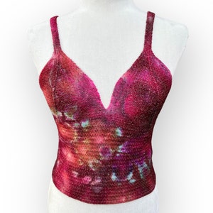 May include: A red, pink, and blue tie-dye tank top with a deep V-neckline. The top is made of a soft, stretchy fabric and has a relaxed fit.