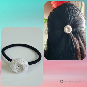 May include: A white crocheted flower hair tie with a black elastic band. The hair tie is shown on a white background and on a person's hair.