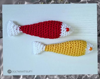 May include: Two crocheted fish, one red and one yellow, with white tails and black eyes. The fish are on a white background.