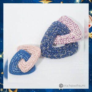 May include: Three crocheted triangle shapes linked together. The shapes are blue with gold flecks and pink with purple flecks.