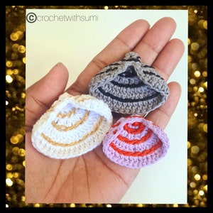 Puede incluir: Tres sombreros de ganchillo en diferentes colores y patrones. Los sombreros son grises con rayas negras, blancos con ribetes dorados y morados con rayas rojas.