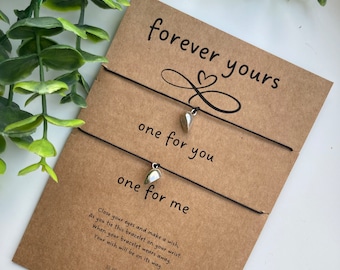 May include: Two friendship bracelets with silver heart charms and a card that reads "forever yours, one for you, one for me". The card also includes instructions on how to make a wish with the bracelets.