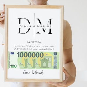 Puede incluir: Una impresión enmarcada con fondo blanco y texto negro. El texto dice "DM Diana & Marius 24.08.2024 Herzlichen Glückwunsch zur Hochzeit und viel Spaß mit eurer ersten Million! 1000000 Eure Schmids". La impresión presenta una imagen estilizada de un billete de 1.000.000 euros.