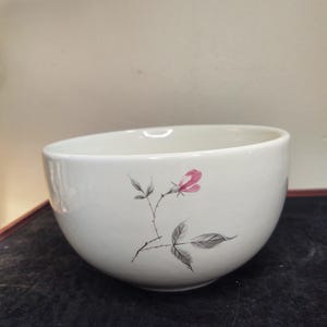May include: A white ceramic bowl with a single pink rose and gray leaves painted on the side.