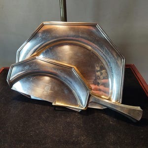 May include: A set of three silver serving trays with octagonal and rounded shapes. The trays are stacked on top of each other and have a polished finish.