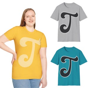 May include: Three t-shirts with a stylized letter T graphic. The shirts are in yellow, gray, and teal.