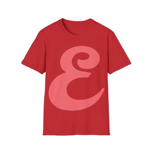 May include: Red t-shirt with a large pink stylized letter "E" printed on the front.