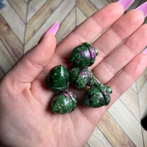 May include: Five green and pink acorn shaped stones. The stones are carved from a green and pink gemstone.