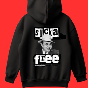 May include: Black hoodie with a graphic design featuring a black and white image of a man in a fedora smoking a cigar. The text "SUCKA FREE" is above and below the image, with additional text at the bottom.