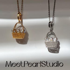 May include: Two pendant necklaces with basket-shaped charms. One is gold-toned, the other silver-toned. Each basket holds pearls and crystals. The text "Meet PearlStudio" is at the bottom.