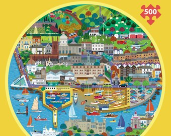 Może przedstawiać: Puzzle 500-elementowe z kolorową ilustracją nadmorskiego miasteczka. Obraz przedstawia budynki, łodzie, most i port. Puzzle są okrągłe z żółtą obwódką.