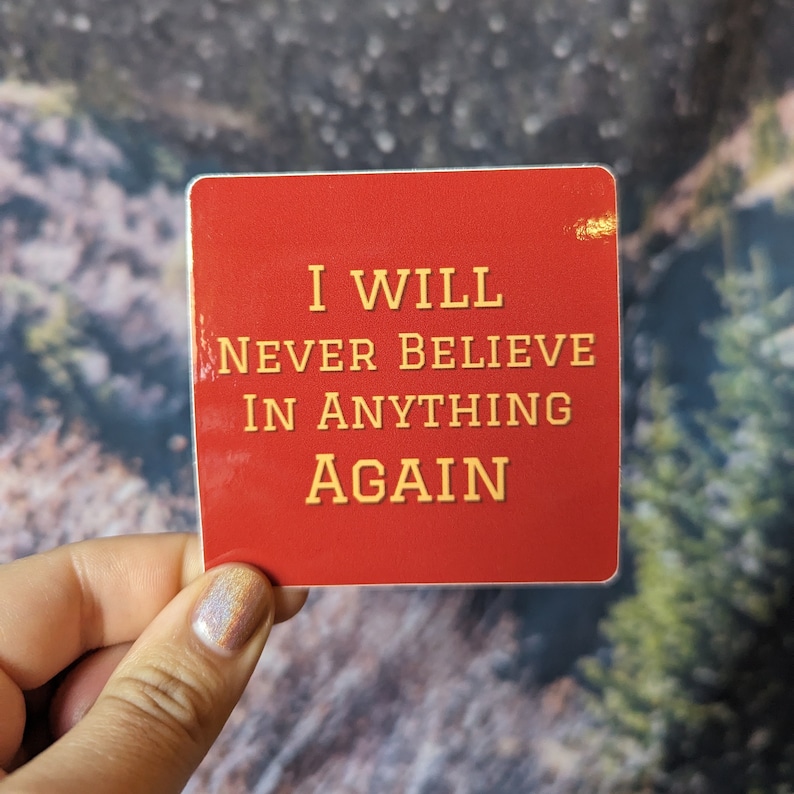 May include: Red square sticker with the text "I WILL NEVER BELIEVE IN ANYTHING AGAIN" in yellow letters.
