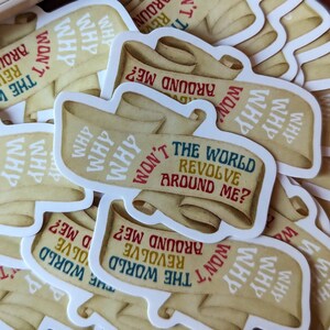May include: A collection of stickers featuring a scroll design with the text "Why won't the world revolve around me?" in various colors. The stickers have a vintage, parchment-like appearance.