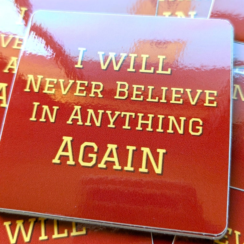 May include: Red square sticker with the text "I will never believe in anything again" in gold lettering.