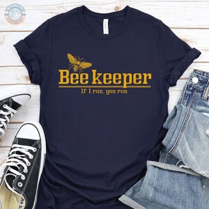 May include: A navy blue t-shirt with a yellow bee graphic and the text "Bee Keeper If I run, you run".