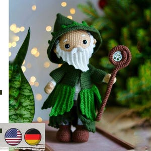 May include: A handcrafted crochet wizard doll in green, beige, and brown. The wizard has a pointed hat, a long white beard, and a staff with a tree design. The image also includes the text "pdf pattern" and two flag icons.