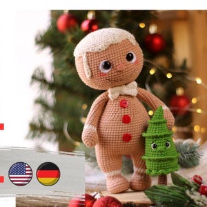 May include: Crocheted gingerbread man amigurumi doll holding a green crocheted Christmas tree. The doll has red buttons and a white bow tie. The doll is standing on a wooden surface with a Christmas tree in the background.
