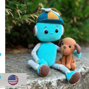 May include: A crocheted turquoise robot doll with a blue and orange hat, gray arms and legs, and brown feet sits next to a small brown crocheted dog. The words "pdf pattern" are written in turquoise on the left side of the image.