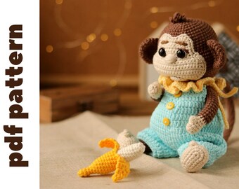 May include: A crocheted monkey toy wearing a blue and yellow outfit, sitting on a beige surface with a yellow crocheted banana beside it.