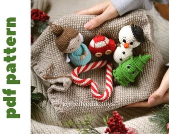 May include: A collection of crocheted Christmas ornaments including a snowman, a candy cane, a Christmas tree, a car, and an angel. The ornaments are displayed on a beige knitted surface.