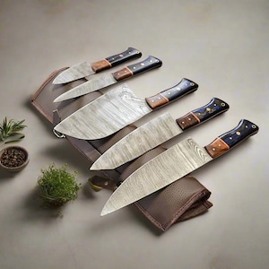 May include: Set of five kitchen knives with patterned blades and wooden handles. The knives are arranged in a brown leather roll.