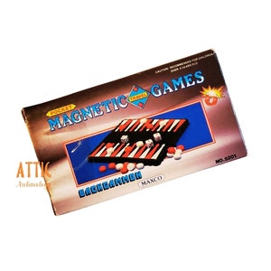 May include: A blue and red box with the words "Pocket Travel Magnetic Games Backgammon" printed on it. The box contains a travel-sized backgammon game with a black and white board and red and white playing pieces. The box also has the words "Maxco" and "No. 5201" printed on it.
