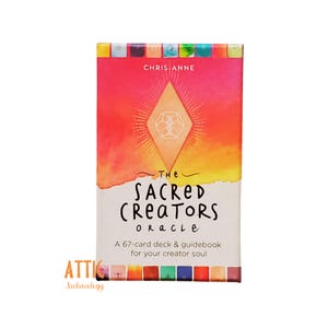 May include: A deck of "The Sacred Creators Oracle" cards. The card deck has a white background with the title in black script. The top of the deck has a colorful watercolor design. The deck includes a 67-card deck and guidebook.