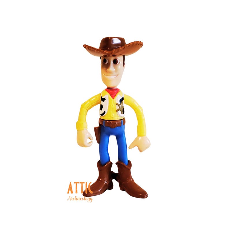 May include: A Woody action figure, featuring a brown cowboy hat, yellow shirt, blue pants, and brown boots. The figure has a sheriff's badge and a red neckerchief. The figure is standing and has a friendly expression.