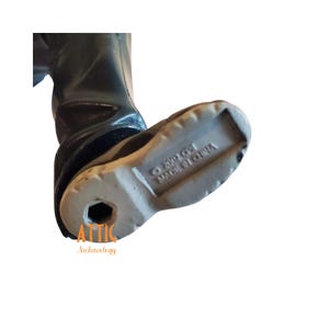May include: Close-up of a black boot with a light gray sole. The sole has a textured design and a hexagonal hole. The text "&copy; 2002 CPI MADE IN CHINA" is visible on the sole. The boot is part of a figurine.
