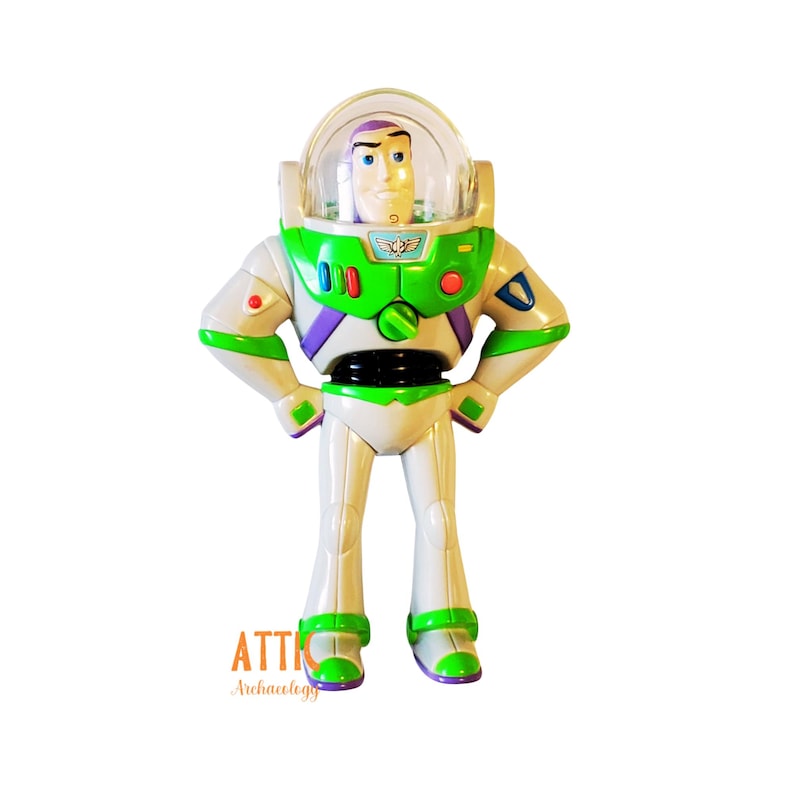 May include: A green, white, and purple plastic toy of Buzz Lightyear from the Toy Story franchise. The toy has a clear plastic helmet with a purple visor and a green and white space ranger suit. The toy is standing with its arms crossed and has a black belt.