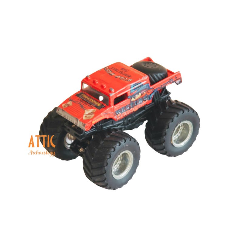 Pode incluir: Brinquedo de caminh&atilde;o monstro vermelho com rodas pretas e um logotipo "Monster Jam" na lateral. O caminh&atilde;o tem um gr&aacute;fico preto e branco de um monstro na lateral e as palavras "Grave Digger" no cap&ocirc;.